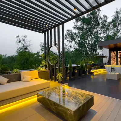 This modern, black metal pergola creates a sophisticated lounge area. The slatted roof offers partial shade, while the under-seat lighting adds a warm glow for evening gatherings.