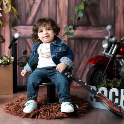 Our little rockstar takes a break from his world tour. This themed toddler photoshoot includes a full set with a guitar, disco ball, and motorcycle prop for a fun and dynamic session.
