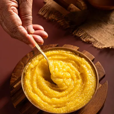 We bring out the story of your product. Here, a hand stirs a bowl of Aazol's ghee, suggesting tradition and authentic preparation, making the product feel personal and trustworthy.