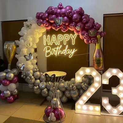 A glamorous 23rd birthday setup. This features a balloon ring with chrome and white balloons, a 'Happy Birthday' neon sign, and large marquee numbers.