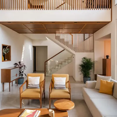 **Amber House, Ahmedabad:** The double-height living space is the core of this home, with a lowered wooden ceiling at the entrance to create a more intimate, welcoming scale. Vertical wooden slats on the upper level unify the space and create a beautiful interplay of light and shadow.
