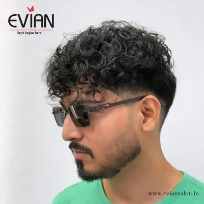 A side profile of this modern curly haircut. The fade is blended perfectly from the temple down, creating a clean and sharp contrast with the textured top.