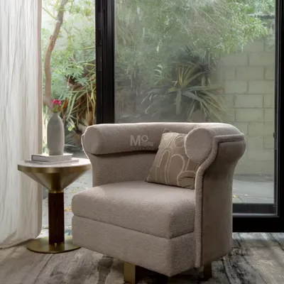 The Sienna Curve Armchair, with its distinctive curved backrest and 360-degree swivel base. Upholstered in a luxurious bouclé fabric with a smooth velvet accent, it's a statement piece perfect for a reading nook or bedroom lounge.