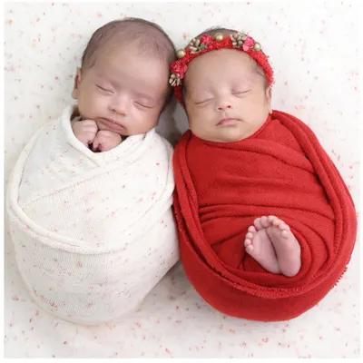 A precious portrait of newborn twins nestled together. We coordinate wraps and poses to showcase their connection while also celebrating their individuality in our specialized twin photoshoots.
