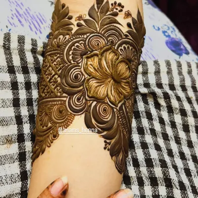 This is a bridal cuff design for the leg, just above the ankle. It features a large, shaded flower as the centerpiece, surrounded by intricate swirls and leaves.