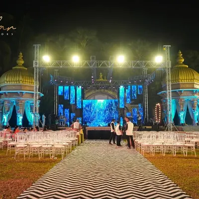 A grand outdoor stage setup for a Sangeet night, complete with a large LED screen backdrop and professional lighting rig. This creates a concert-like feel for the performances.