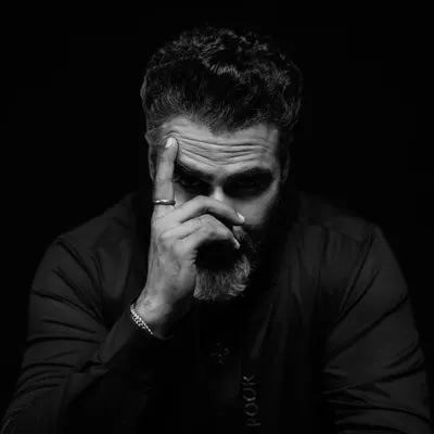 A study in stillness and thought. This low key portrait uses deep shadows to draw all attention to the subject's intense expression, creating a frame that feels like a scene from a film.