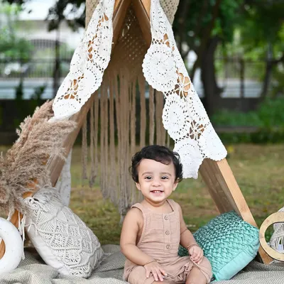 A happy little camper enjoying the outdoors. This boho-themed outdoor session with a lace teepee and natural textures is perfect for capturing a baby's adventurous spirit.