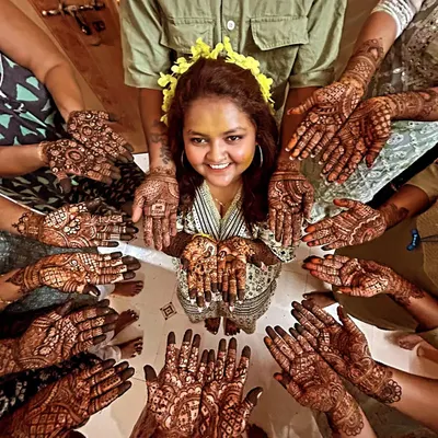 The quintessential mehendi ceremony photo. A radiant bride surrounded by her 'team bride', all showing off their beautiful henna. It's a moment of pure joy and togetherness.