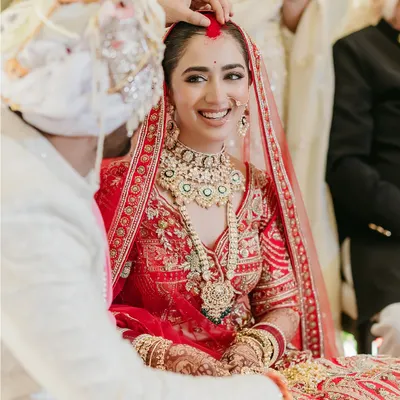 A beautiful, candid moment during the ceremony, capturing the bride's joyful smile as the groom applies the sindoor.