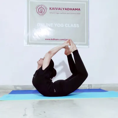 A practitioner demonstrates Dhanurasana (Bow Pose), an effective backbend for strengthening the back muscles and improving posture. This asana is performed in our online class setup, showing our commitment to proper form even in a virtual setting.