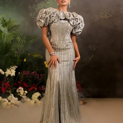 The Bellerose Gown in silver, featuring a fully embellished mermaid silhouette and dramatic 3D ruffled sleeves. This piece is a testament to sculptural, wearable art.