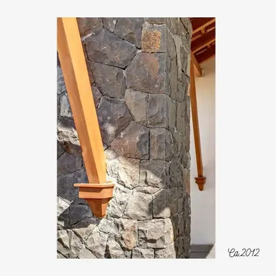 A detail of a stone column meeting a wooden support beam at the Lake Pawana Resort, built circa 2012. This junction highlights the honest expression of materials, where the texture of the local stone contrasts with the smooth finish of the timber.