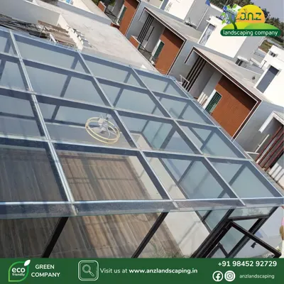 An aerial view of the custom-built glass room for the CEO of IFB Industries Ltd. This shot shows the clear toughened glass roof, which allows for maximum natural light while protecting the interior from the elements.