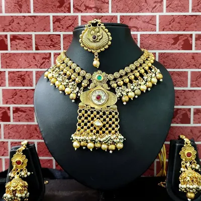 A beautiful antique gold-finish set with a unique design, featuring a choker, matching earrings, and a maang tikka.