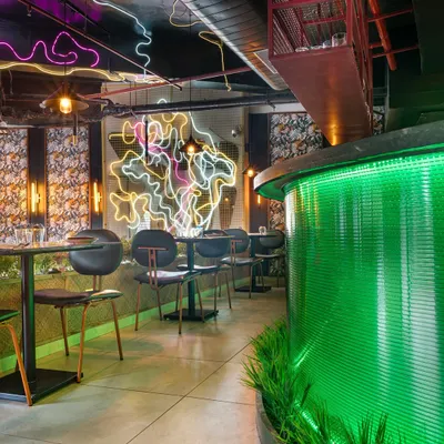 An overview of Burosu restaurant, where a glowing green fluted glass bar and custom neon art create a vibrant, street-style pulse. The design uses layers of light, texture, and color to create an immersive pan-Asian dining experience.