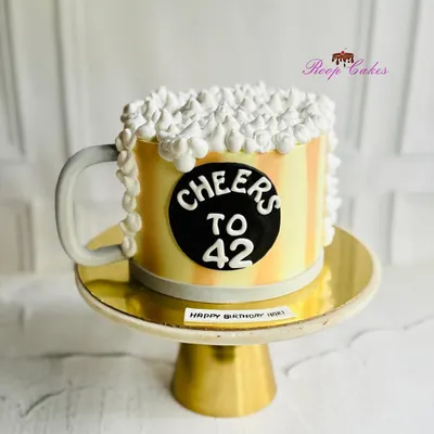 Cheers to 42. This fun birthday cake is shaped like a frothy mug of beer, complete with a handle and overflowing whipped cream foam. It's a perfect and playful cake for a beer lover's celebration.