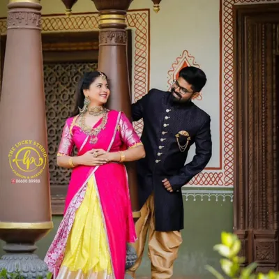 This coordinated set is perfect for a vibrant pre-wedding shoot. It features a bright pink and yellow lehenga paired with a classic navy blue sherwani with gold buttons.