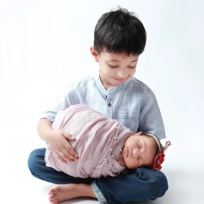 A big brother's gentle protection. He looks down at his sleeping newborn sister with so much love and care.