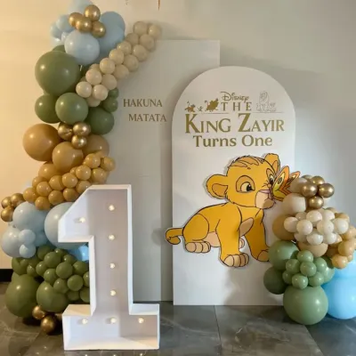 Another take on the Lion King theme for a first birthday. This one features a 'Hakuna Matata' backdrop with a large light-up number '1' and a cute cutout of baby Simba.