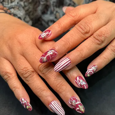 This festive design features a mix of hand-painted candy cane stripes and glittery red nails with bow details. It’s a perfect example of detailed holiday art.