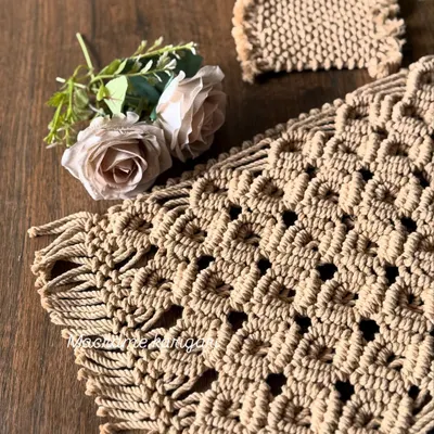 A close-up of our macramé placemat, showing the intricate diamond pattern and fringed edges. This piece adds texture and a bohemian feel to your table setting.