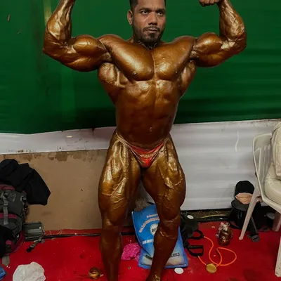 Backstage at the Mr. India competition, hitting a front double bicep pose. This is the final look before stepping on stage, the result of months of preparation.