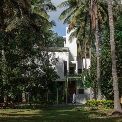 The SANCTUM House, viewed from the surrounding coconut grove. The design's primary goal was to integrate the home into the landscape, preserving existing trees and creating a structure that feels like a natural extension of the orchard.
