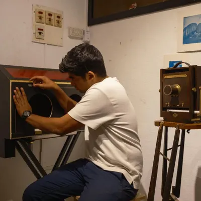 An artist works with a portable wet plate collodion setup, a complex and historic process that we support at our studio. This image shows the dedication involved in handmade photography.