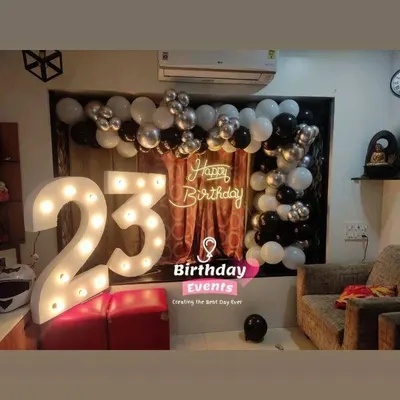 A sleek and modern setup for a 23rd birthday. The large marquee numbers are paired with a simple black, white, and silver balloon arch for a cool, understated look.