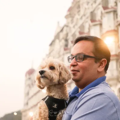 A happy portrait of Aaloo the poodle and his dad, sharing a joyful moment in front of the Taj Mahal Palace Hotel in Mumbai.