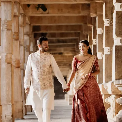 A beautiful couple during their pre-wedding shoot. The bride-to-be is wearing a traditional red and cream brocade half-saree, perfect for creating timeless and romantic memories against a heritage backdrop.