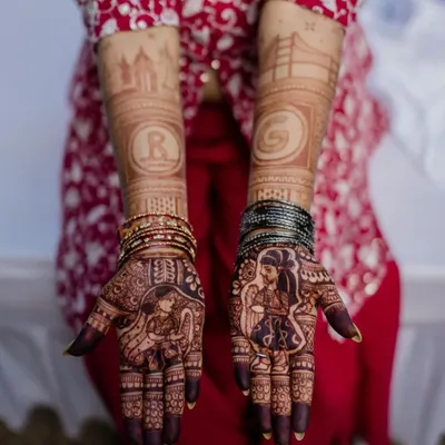 A perfect couple shot showing the bride's portrait mehendi and the groom's simpler initial design. This design also features the skylines of Bangalore and San Francisco.