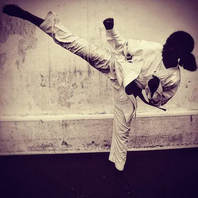 A silhouette of a female student executing a flawless high kick. This image captures the grace, power, and confidence that our training instills.