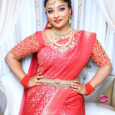 A full-length view of a gorgeous South Indian bridal look. The red Kanjivaram saree is draped perfectly, and the look is completed with a waist belt and traditional gold jewellery.