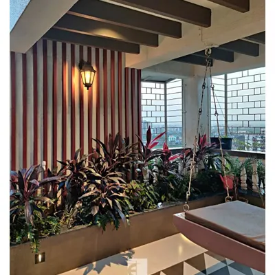 This terrace is designed as an urban sanctuary. It features a large wooden swing, a planter bed with tropical plants, and a striking geometric tile pattern on the floor, all framed by wooden ceiling rafters.