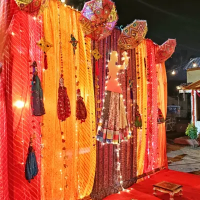 A traditional baby shower (Dohale Jevan) decoration with colorful drapes, Rajasthani puppets, and umbrellas, creating a festive and cultural theme.