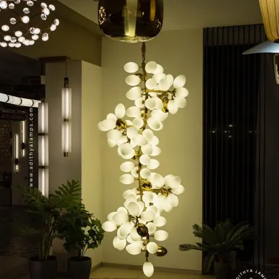 A true centerpiece, this double-height chandelier features a cascade of white and gold ovals. It is designed to fill grand foyers and living spaces with a spectacular, diffused light that is both impressive and welcoming.