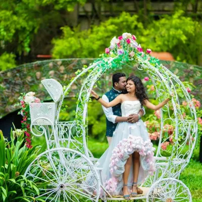 Create a fairytale moment with this whimsical couple's outfit. The high-low gown with floral details and the partner's Nehru jacket are perfect for a romantic shoot with props like this beautiful white carriage.