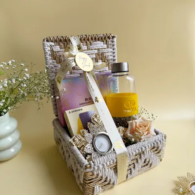A beautiful corporate Diwali hamper designed for TATA, featuring a custom-branded water bottle, assorted treats, and a festive diya, all packed in an elegant woven basket.