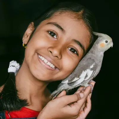 The bond between a child and a pet is truly special. This girl's bright smile as she cuddles her cockatiel is a perfect example of the pure, simple joy I love to photograph.