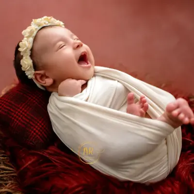 An unposed, beautiful moment of a newborn baby yawning while wrapped snugly in a white swaddle. These are the real, fleeting expressions I love to capture.