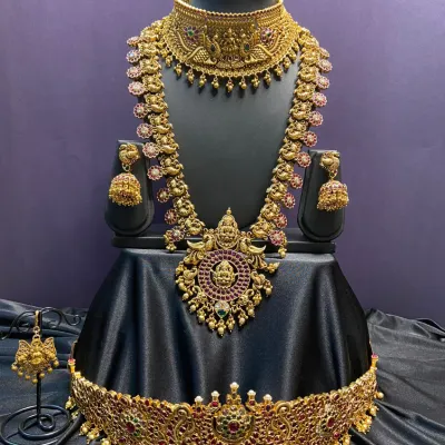 A complete antique bridal set featuring a wide choker, a long haaram with deity pendants, and a matching vaddanam. The intricate design and kemp stones make this a perfect choice for a traditional muhurtham look.