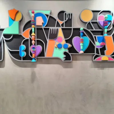 Titled 'Onwards and Upwards', this vibrant mixed-media installation is about personal growth. The piece combines layered MDF, abstract shapes, and hand-painted Channapatna wooden beads to create a colorful, joyful composition that bursts with positive energy.