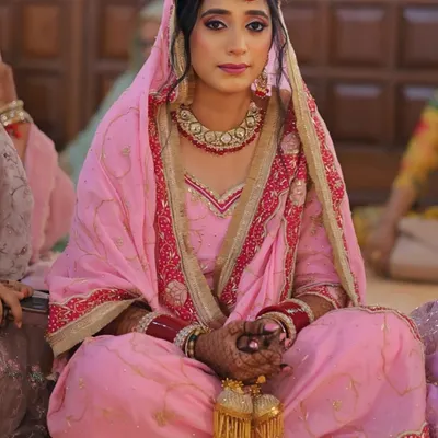 A classic Punjabi bride, radiating grace and serenity. I focused on creating a flawless base with defined eyes and a soft pink lip to complement her beautiful pink wedding suit and traditional jewelry.