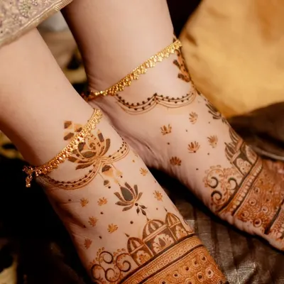 A delicate foot mehendi design that complements the bride's anklets. The pattern features a simple band on the foot with light, scattered motifs extending towards the ankle.