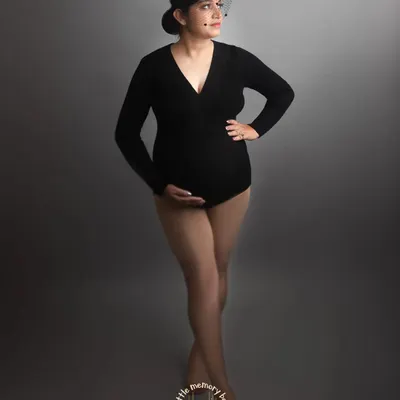 A classic black bodysuit against a simple grey backdrop creates a sophisticated and timeless maternity portrait. This look is all about celebrating the powerful and beautiful shape of your body during pregnancy.