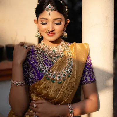 The golden hour light perfectly complements this stunning Kanchi tissue saree. This shot highlights the rich purple blouse and the intricate diamond and emerald jewelry, creating a portrait of pure elegance.