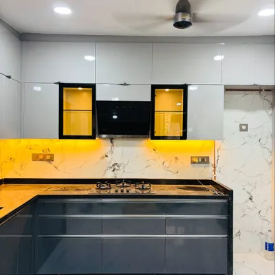 A complete view of a two-tone L-shaped kitchen with glossy white upper cabinets and dark grey lower units. The design features yellow-tinted glass shutters and a built-in hob on a black granite countertop.