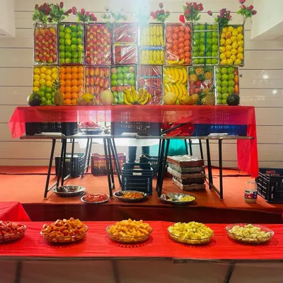 Our grand fruit display table. We create an impressive wall of fresh fruits like apples, oranges, bananas, and pineapples, with cut fruit platters ready for guests to enjoy.